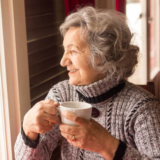 Old lady sat drinking tea coffee looking to right