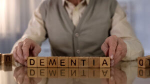 Old,Man,Making,Word,Dementia,Of,Wooden,Cubes,On,Table,